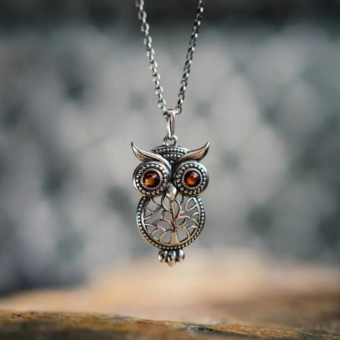 Vintage steampunk owl pendant necklace front close-up displaying intricate carved details, linked metal chain, and amber eyes against natural wooden background