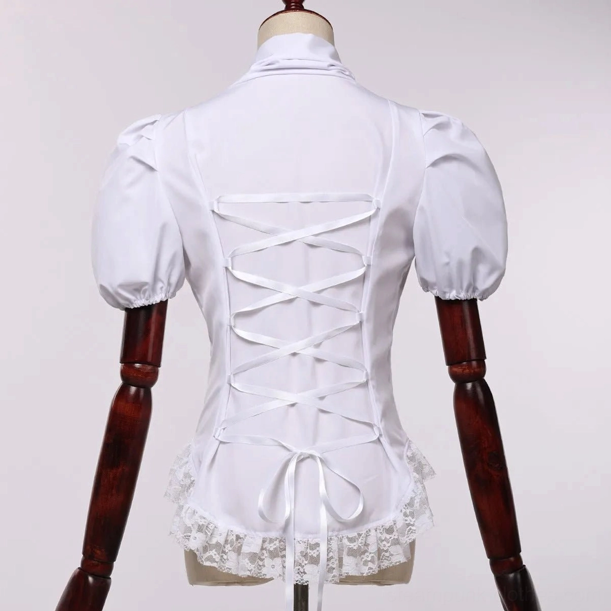 White corset-style puff sleeve steampunk shirt with back lace-up closure, lace-trimmed hem and high collar, displayed on dress form mannequin rear view