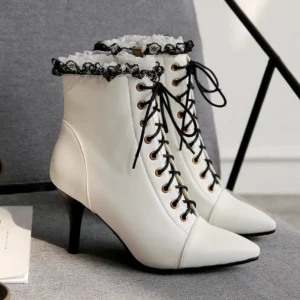 White steampunk Victorian lace-up heeled ankle boots with black ruffled lace trim, pointed stiletto toe, and gold-toned lace eyelets - three-quarter side view