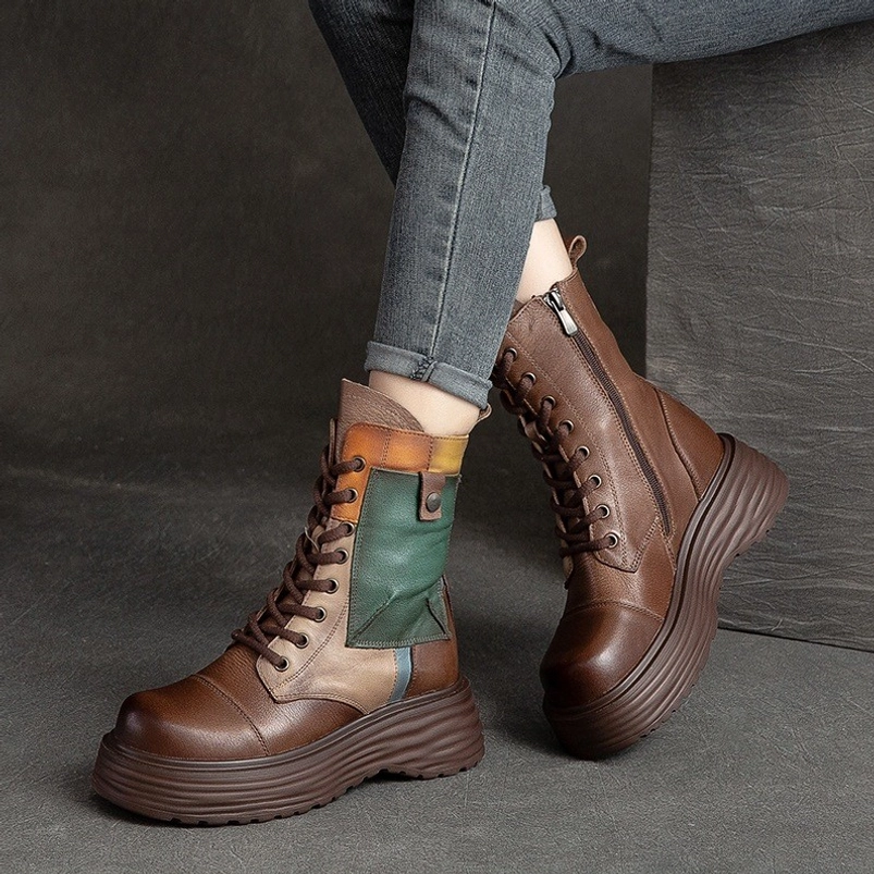 Woman wearing steampunk platform combat boots with blue denim pants, low side view highlighting chunky platform outsole and multi-tone leather construction on studio backdrop