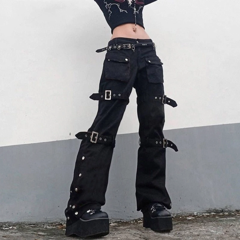 Women's black steampunk cargo pants with silver buckles worn by model in outdoor setting, featuring low-rise design and side snap fasteners