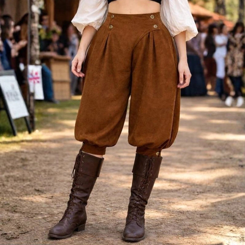 Women's steampunk pirate breeches front view, brown suede fabric with pleated front, buttoned waist, and cropped gathered leg cuffs, worn by female model outdoors at renaissance fair