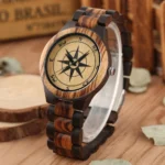 Wooden compass steampunk watch with two-tone wood grain and metal crown, displayed on rustic wooden desktop with vintage styling